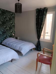 um quarto com 2 camas, uma cadeira e uma janela em Auberge des chemins em Moissac