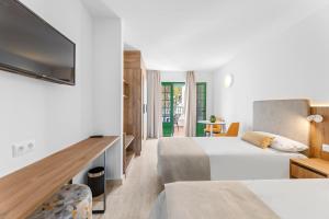 a hotel room with two beds and a flat screen tv at Apartamentos Tropicana in Puerto del Carmen