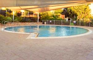 a large swimming pool with an umbrella on a patio at Lavi Kibbutz Hotel in Lavi