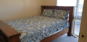 een bed met een blauw en wit dekbed met een houten frame bij Standard Queen size bedroom in Little River