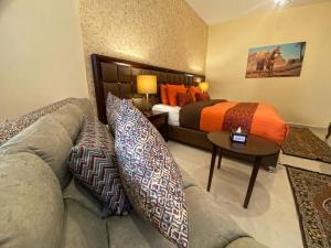 um quarto de hotel com uma cama e um sofá com almofadas em Anbat Midtown Hotel em Wadi Musa