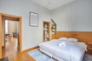 Schlafzimmer mit einem weißen Bett mit einem Kopfteil aus Holz in der Unterkunft Apartment Ile Saint Louis by Studio prestige in Paris