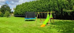 two swings in a grassy yard with a playground at Villa with covered and heated swimming pool in Thiberville