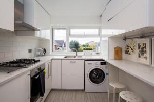 a white kitchen with a washing machine and a sink at Stylish and Cosy 1 BDR Apt, Ealing Broadway in London