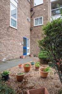 a group of potted plants in front of a brick building at Stylish and Cosy 1 BDR Apt, Ealing Broadway in London