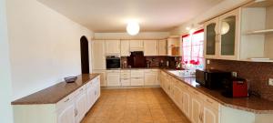 a large kitchen with white cabinets and a counter top at Villa with covered and heated swimming pool in Thiberville