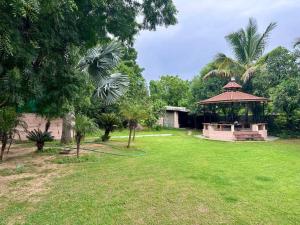 een grote tuin met een prieel en bomen bij Farm stay in Ahmedabad in Ahmedabad