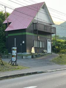 uma casa com um telhado vermelho com uma placa em frente em Kohan no yado Kojima em Lago Toya