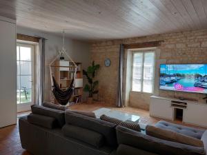 a living room with a couch and a flat screen tv at Maison pour 6 personnes avec piscine et proche de la plage in Aytré