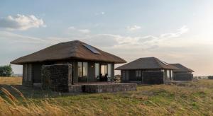 two huts in a field with the sky at Serengeti Mara River Camp in Robanda