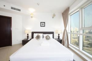 a white bedroom with a large bed and a window at SHH - Furnished 1BR Apartment in Goldcrest Executive, Jumeirah Lake Towers in Dubai