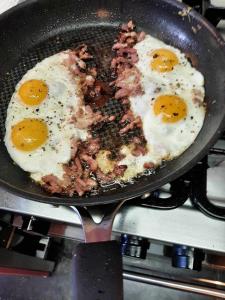 two eggs are being fried in a pan on a stove at Couleur Campagne in Theux