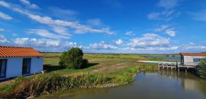 a view of a river with houses and a bridge at Au cœur du marais breton in Bois-de-Cené