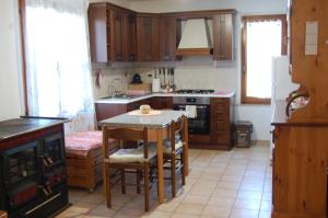 una cocina con armarios de madera y una mesa con sillas. en Casa Vacanze La Rosa e L'Ulivo, en Faiti