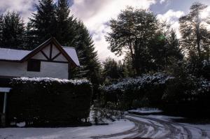 a snow covered road next to a house with trees at Pura Patagonia in Villa La Angostura