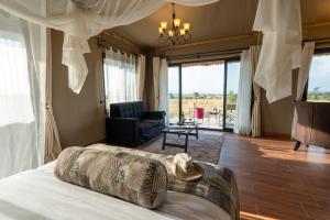ein Schlafzimmer mit einem Bett und ein Wohnzimmer in der Unterkunft Serengeti River Camp in Robanda
