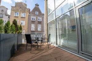 a balcony with chairs and a table and windows at VIU Apartament z tarasem w sercu Gdańska in Gdańsk