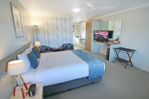 a hotel room with a large bed and a desk at Whangaparaoa Lodge in Whangaparaoa