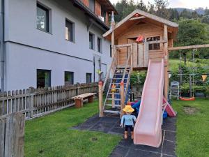 ein Kind steht auf einem Hof mit Spielplatz in der Unterkunft Appartement Fromme Helene in Millstatt