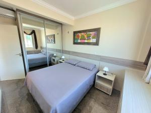 1 dormitorio con 1 cama grande y espejo en Mariscal, en Bombinhas