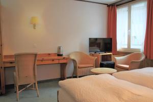 a hotel room with a desk and a television at Self-Service Guesthouse Berggeist in Saas-Fee +21 photos