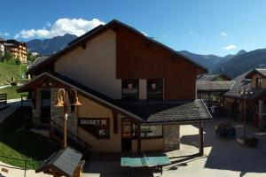 a building with a roof with mountains in the background at Paradiski ski au pied vallandry in Landry