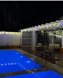 a swimming pool at night with a table and chairs at Al Sharq Holiday Home in Khor Fakkan