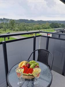 a plate of fruit on a table with two wine glasses at Apartament Aleje Józefa Piłsudskiego in Nowy Sącz