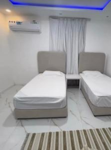 a bedroom with two beds and a table and a window at Al Sharq Holiday Home in Khor Fakkan