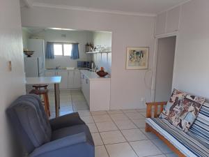 a living room with a blue couch and a kitchen at 4 On Hoffman Seaview in Agulhas