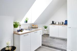 una cocina con armarios blancos y fregadero en Schlossberg Residences - XXL-Design-Apartment mit Schlossblick für bis zu 10 Personen en Schwetzingen