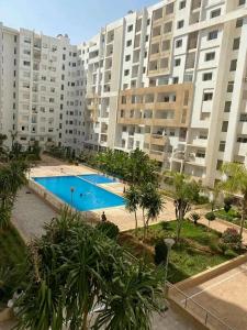 a large apartment complex with a swimming pool in front of buildings at Appartement meublé in Agadir