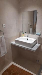 La salle de bains est pourvue d'un lavabo blanc et d'un miroir. dans l'établissement Appartement meublé, à Agadir