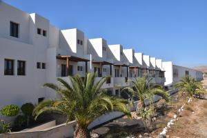 eine Reihe weißer Gebäude mit Palmen in der Unterkunft Casa Milan in Puerto Calero