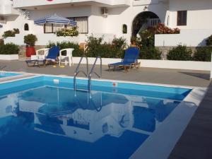 a swimming pool with two chairs and a house at Villas Michalis in Chorafakia