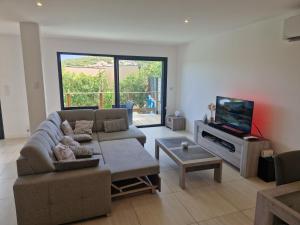 a living room with a couch and a tv at Villa Favone 4 chambres piscine privée in Conca