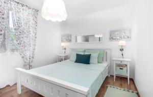 a white bedroom with a large bed with blue pillows at Abby in Dramalj