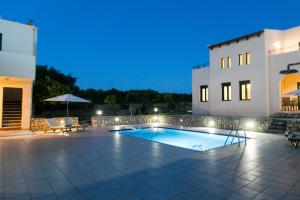 a swimming pool in front of a house at night at Villa Eleni in Asprouliánoi