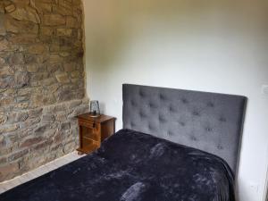 a bedroom with a bed and a stone wall at KERHAM in Plouay