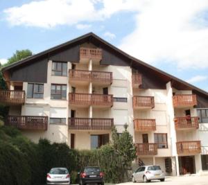 un gran edificio de apartamentos con coches aparcados frente a él en Haut Doubs Belvédère, en Les Hôpitaux-Neufs