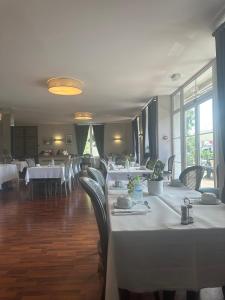 uma sala de jantar com mesas e cadeiras brancas em Hôtel du Rangen em Thann