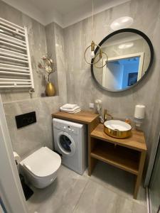 a bathroom with a washing machine and a mirror at Margaret apartament in Świnoujście