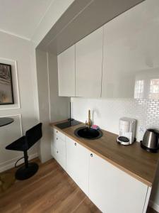 a kitchen with white cabinets and a sink at Margaret apartament in Świnoujście