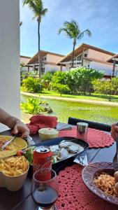 Taiba Beach Resort Casa com piscina في تايبا: طاولة عليها طعام مع أشجار النخيل في الخلفية