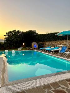 ein großer blauer Pool mit Stühlen und einem Sonnenschirm in der Unterkunft Villa Luca in Budoni
