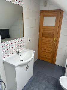 a white bathroom with a sink and a wooden door at Apartament D&D in Gorlice