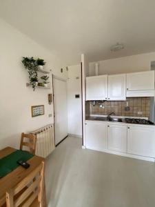 a kitchen with white cabinets and a table in a room at Dimora Sofia in Rovetta