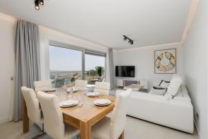 ein Esszimmer mit einem Tisch und einem weißen Sofa in der Unterkunft Modern holiday apartment with incredible sea views in La Cala de Mijas in Málaga