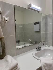 uma casa de banho com um lavatório, um espelho e uma banheira em Hôtel du Rangen em Thann