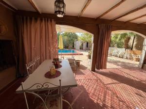 una camera con tavolo e patio con piscina di Dar Jamila Agafay - Ait Imour a Marrakech